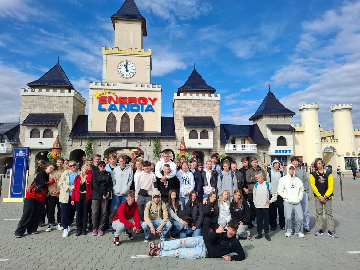 Grupa młodzieży pozuje do zdjęcia przed wejściem do parku rozrywki Energylandia.