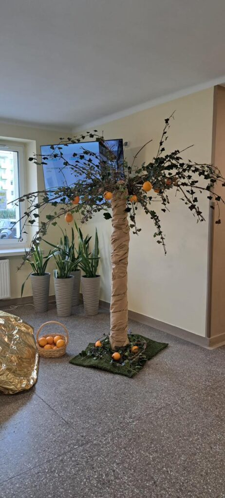 Sztuczne drzewo z papierowym pniem i pomarańczami jako dekoracja w pomieszczeniu.